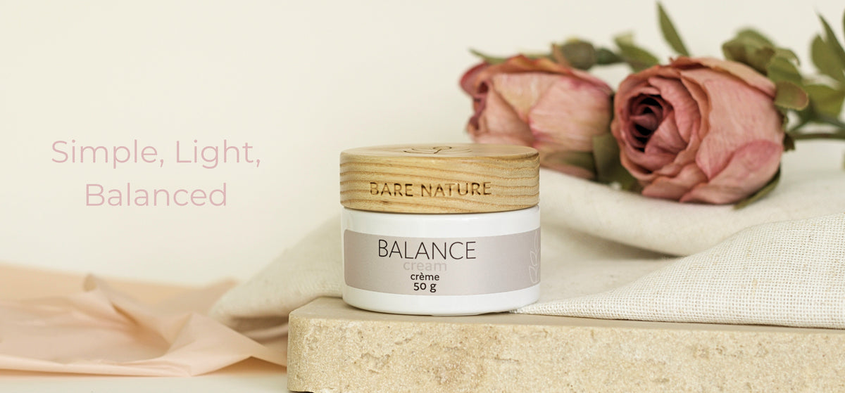 A cosmetic cream jar labeled 'BARE NATURE BALANCE cream 50 g' sits on a stone slab with pink roses and a cream fabric in the background. Pink text on the left reads 'Simple, Light, Balanced'.