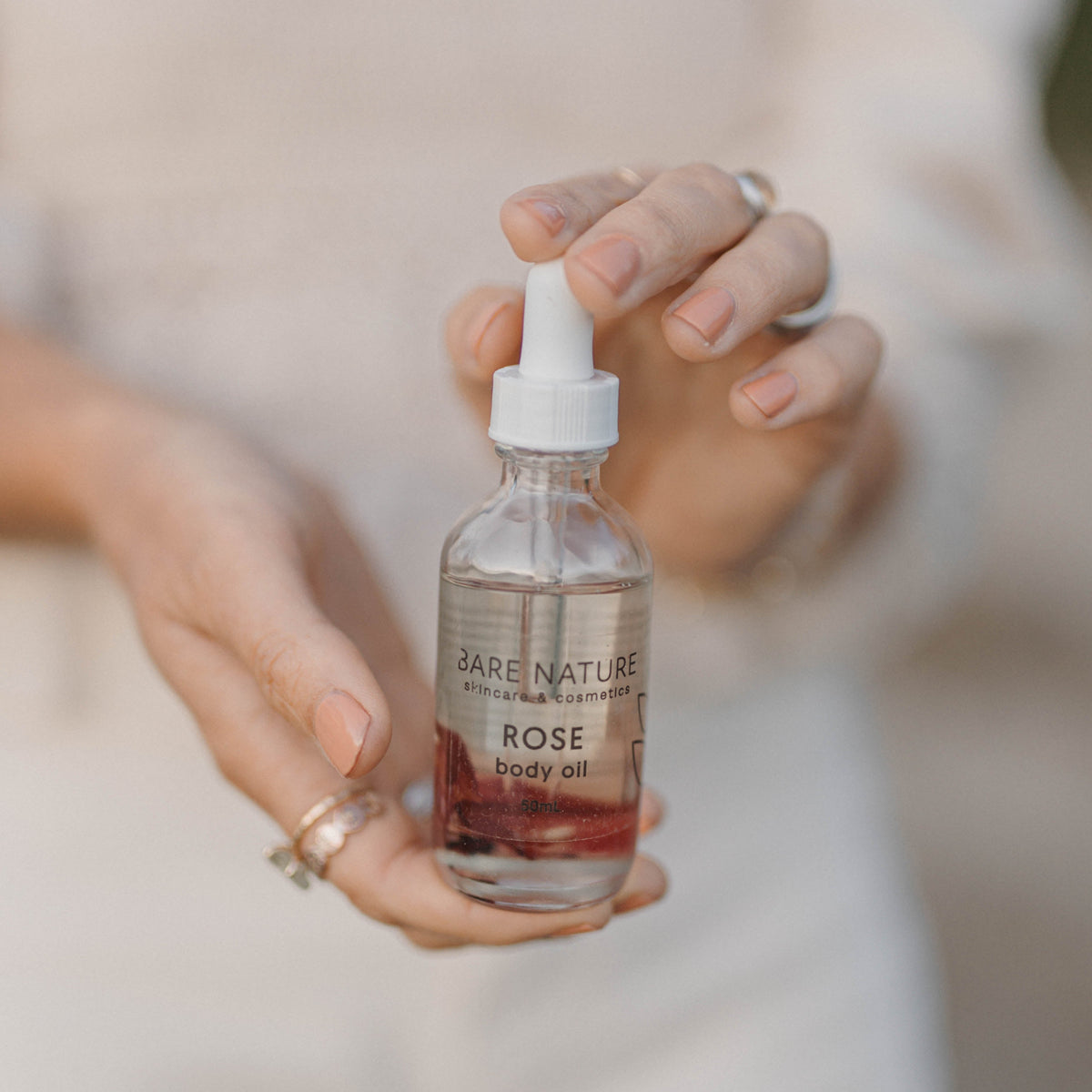 Person holding a bottle of 'Bare Nature' rose product.