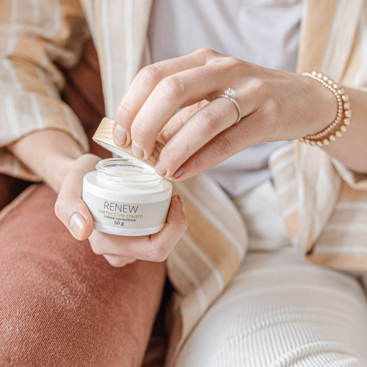 A woman opening a jar of Bare Nature Skincare Renew Corrective Cream - designed for deep hydration with Hyaluronic acid and Rosehip oil