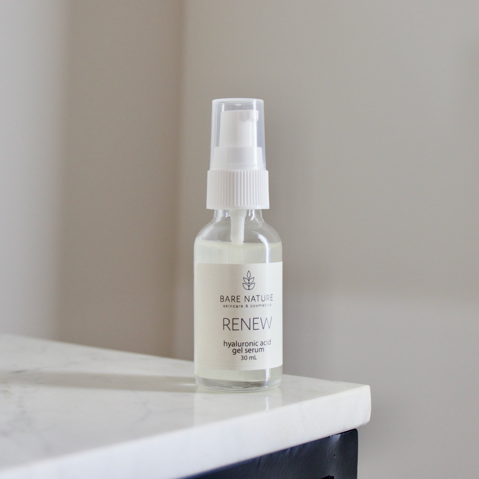 A clear glass jar with a pump dispenser containing the Renew Hyaluronic Acid Gel Serum, placed on a white surface.